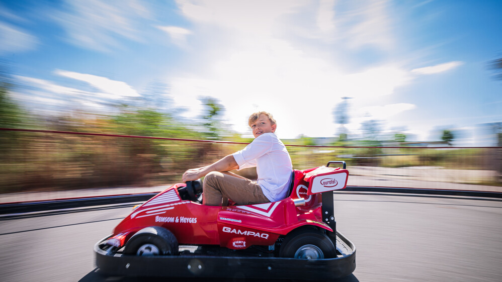 Junge bei voller Fahrt auf einem E-Kart.